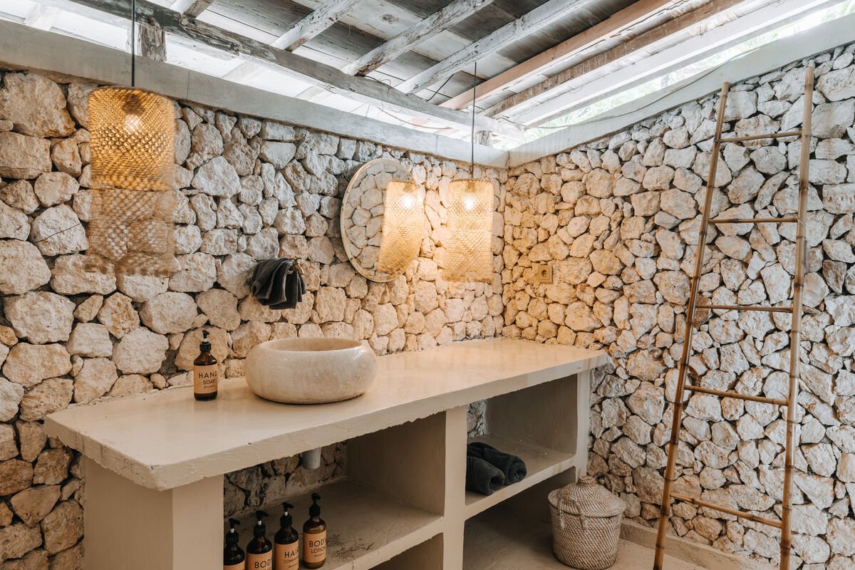 Premium bungalow stone bathroom with a round mirror