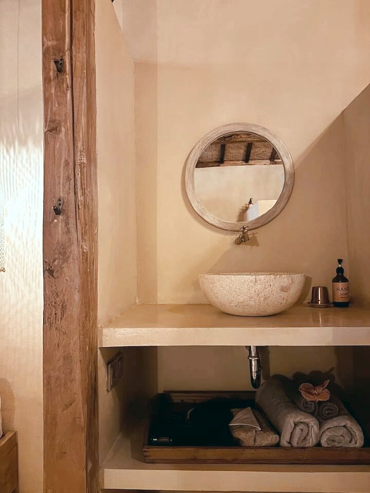 Single room washbasin with a round mirror and fresh towels