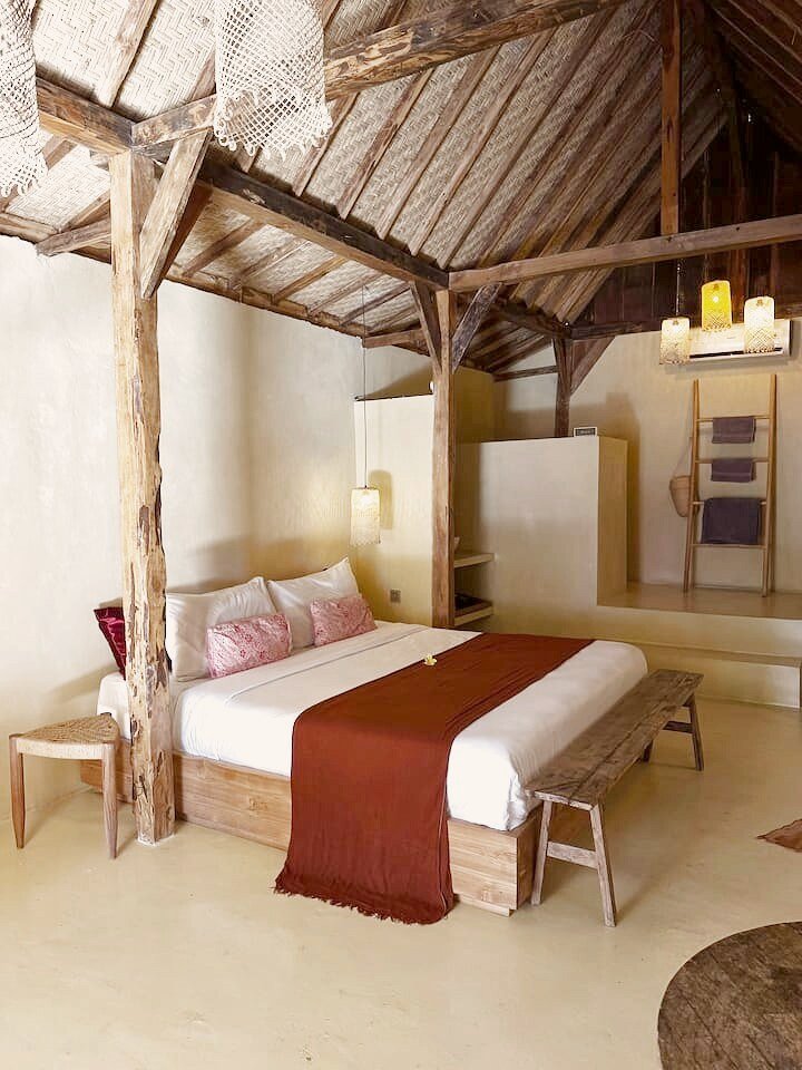 Single room with a neatly made bed under a high wooden roof